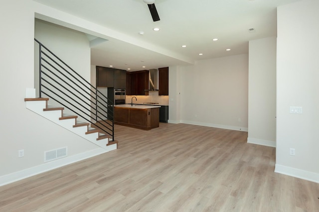 unfurnished living room featuring visible vents, recessed lighting, stairs, light wood finished floors, and baseboards