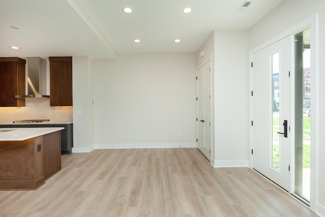 interior space with visible vents, wall chimney range hood, light countertops, light wood-style floors, and recessed lighting