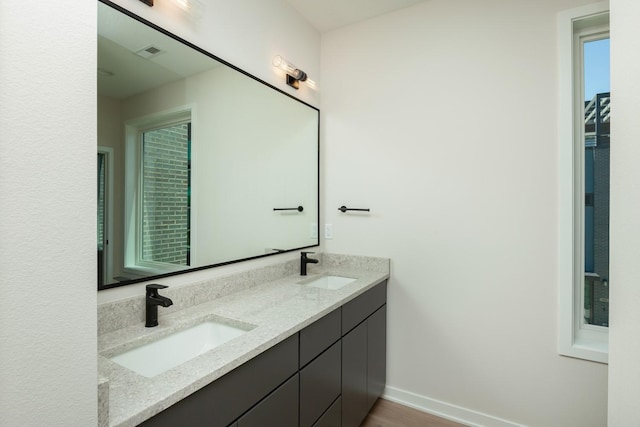 full bath with baseboards, double vanity, a sink, and visible vents