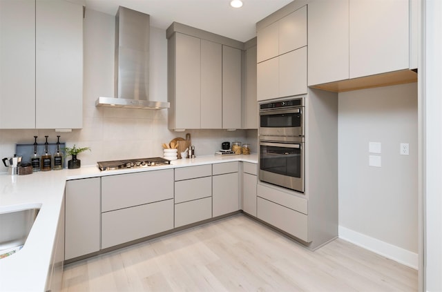 820 E 2nd St, Des Moines, IA 50309 - kitchen featuring wall chimney exhaust hood, light wood-style flooring, appliances with stainless steel finishes, light countertops, and gray cabinetry