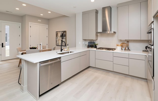 820 E 2nd St, Des Moines, IA 50309 - kitchen featuring gray cabinets, wall chimney range hood, a peninsula, appliances with stainless steel finishes, and a sink