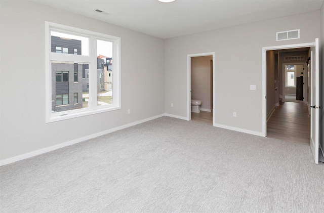 820 E 2nd St, Des Moines, IA 50309 - unfurnished bedroom with light colored carpet, baseboards, multiple windows, and visible vents