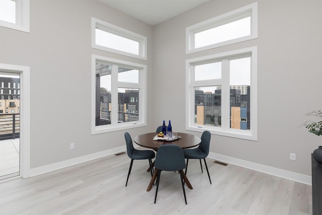820 E 2nd St, Des Moines, IA 50309 - dining room with visible vents, baseboards, a high ceiling, and light wood-style floors