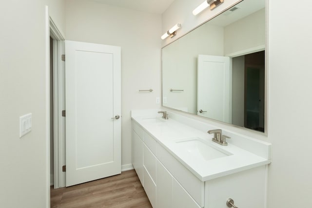 822 E 2nd St, Des Moines, IA 50309 - bathroom featuring double vanity, visible vents, a sink, and wood finished floors