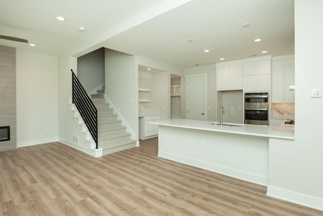 822 E 2nd St, Des Moines, IA 50309 - kitchen featuring white cabinets, a sink, light wood-style floors, recessed lighting, and stainless steel double oven