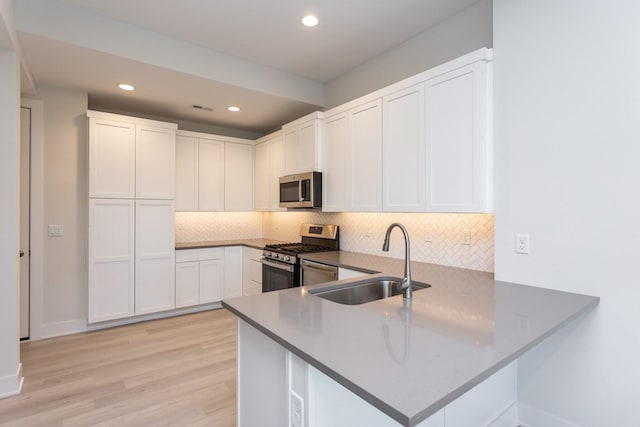kitchen with a peninsula, recessed lighting, appliances with stainless steel finishes, a sink, and decorative backsplash