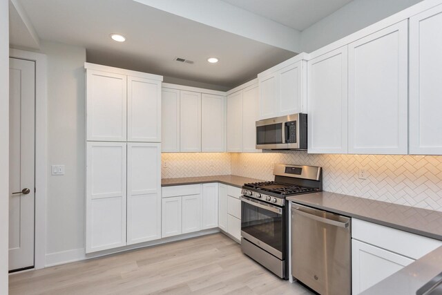 kitchen featuring white cabinets, visible vents, decorative backsplash, and appliances with stainless steel finishes
