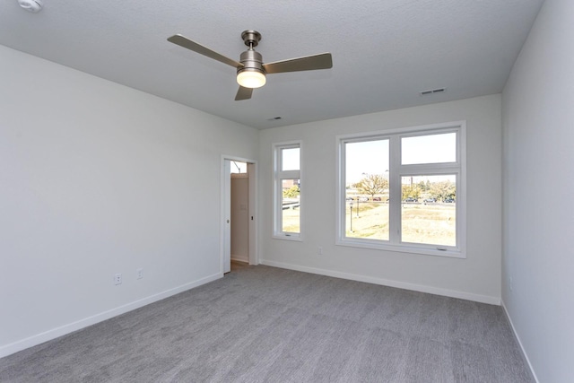 carpeted empty room with baseboards, a ceiling fan, and a wealth of natural light
