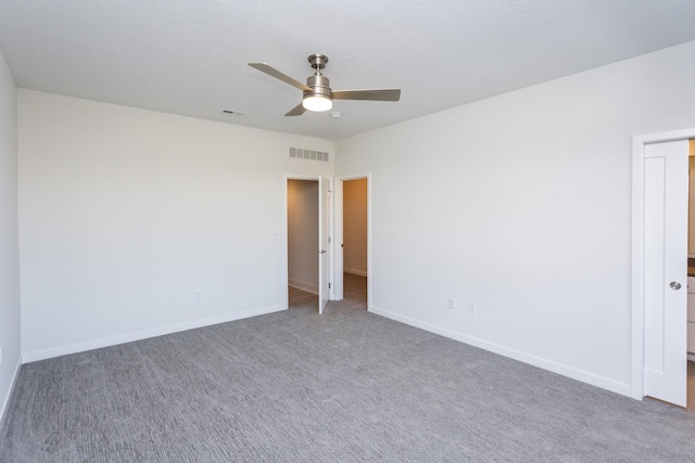 carpeted spare room with visible vents, baseboards, and a ceiling fan