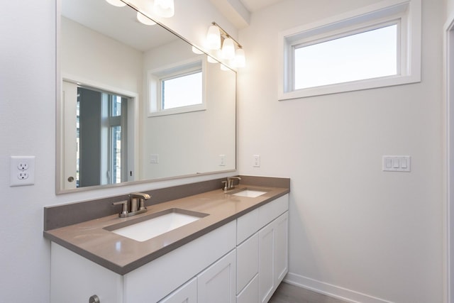 full bath featuring double vanity, a sink, and baseboards