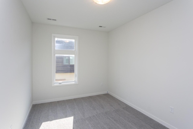 carpeted empty room featuring baseboards and visible vents