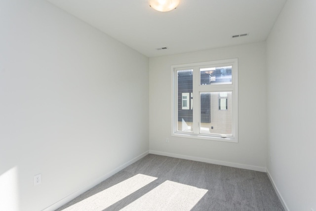 empty room with carpet flooring, visible vents, and baseboards