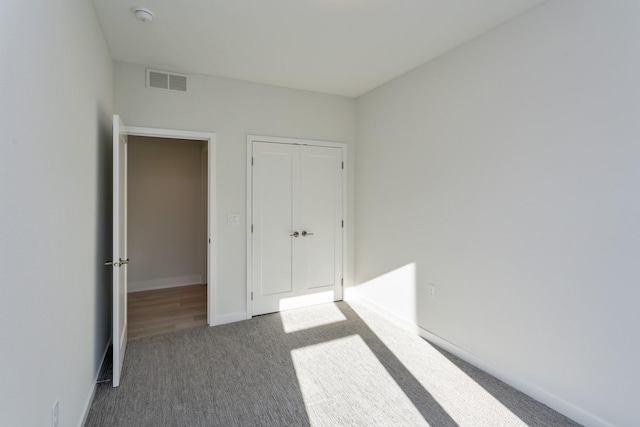 unfurnished bedroom with visible vents, a closet, baseboards, and carpet floors