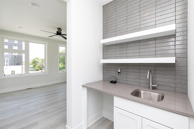 225 Maple St, Des Moines, IA 50309 - interior space with light wood-style flooring, a ceiling fan, white cabinets, a sink, and baseboards
