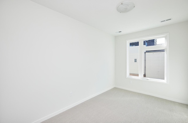empty room with baseboards, light carpet, and visible vents