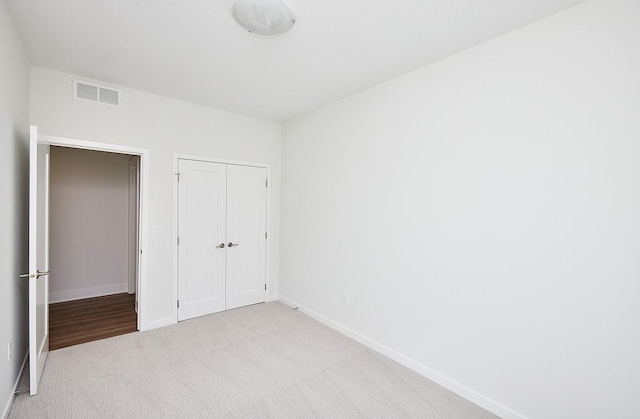 unfurnished bedroom with carpet floors, a closet, visible vents, and baseboards