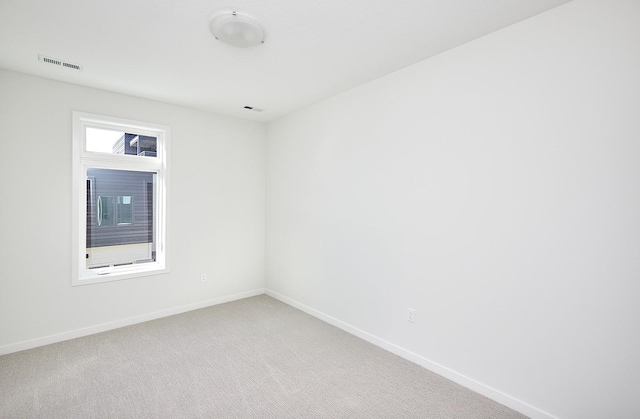 empty room with baseboards, visible vents, and light colored carpet