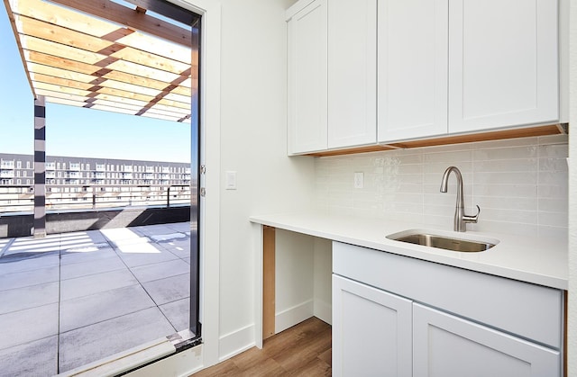 interior space featuring a sink, light wood-style floors, light countertops, backsplash, and white cabinetry