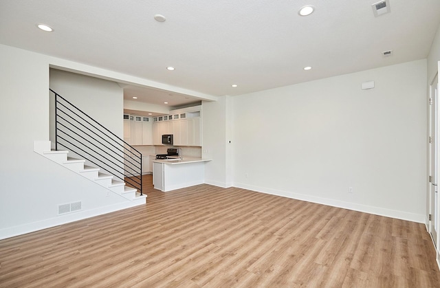 unfurnished living room with recessed lighting, light wood-type flooring, and visible vents
