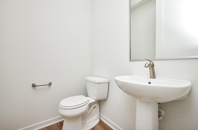 bathroom featuring wood finished floors, baseboards, a sink, and toilet