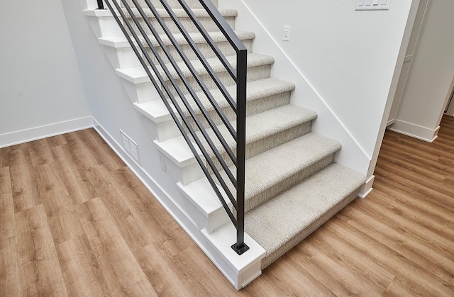 stairway with wood finished floors, visible vents, and baseboards
