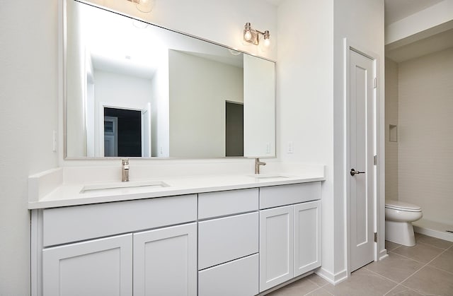 bathroom with a sink, toilet, double vanity, and tile patterned flooring