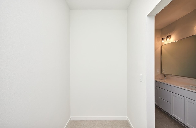 bathroom with double vanity, a sink, and baseboards