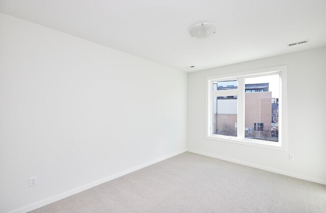 empty room with visible vents, baseboards, and light carpet