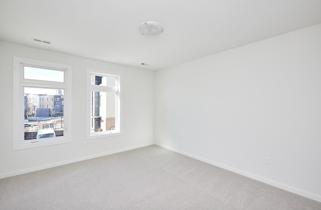 unfurnished room featuring visible vents, baseboards, and light carpet