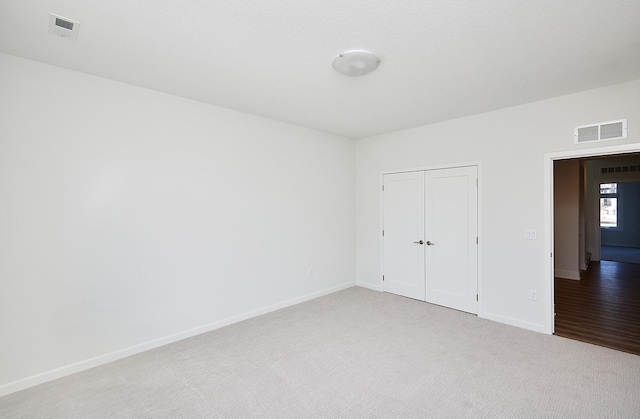 unfurnished bedroom featuring visible vents, baseboards, a closet, and carpet
