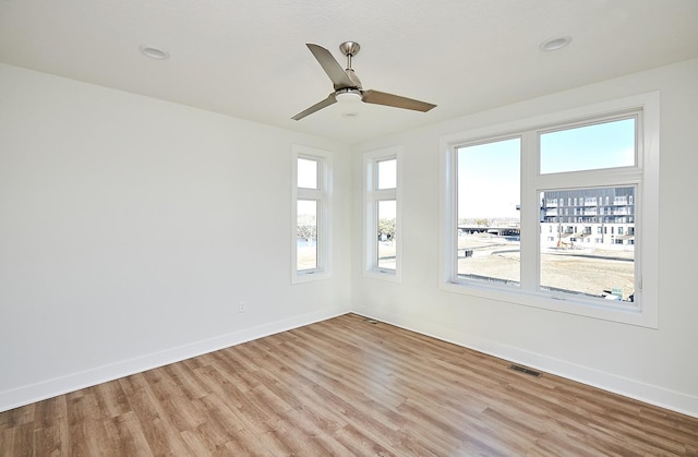 empty room with light wood-type flooring, ceiling fan, baseboards, and visible vents