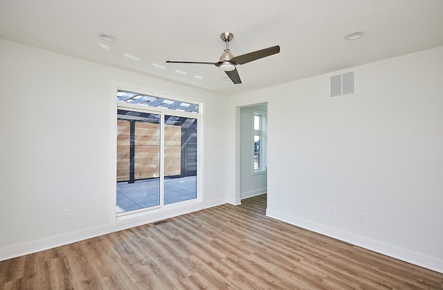 unfurnished room with wood finished floors, baseboards, a ceiling fan, and visible vents
