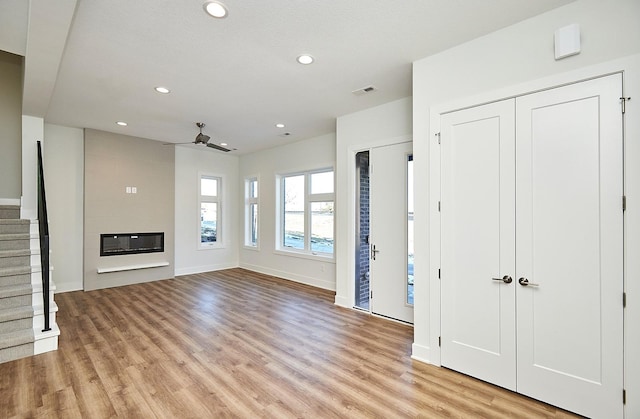 unfurnished living room with light wood-type flooring, recessed lighting, stairway, visible vents, and ceiling fan