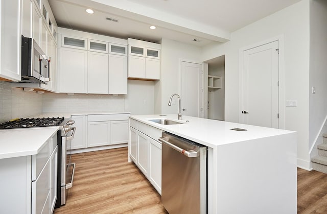 kitchen featuring recessed lighting, a sink, stainless steel appliances, light wood finished floors, and decorative backsplash
