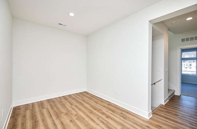 unfurnished room with light wood-type flooring, baseboards, visible vents, and recessed lighting