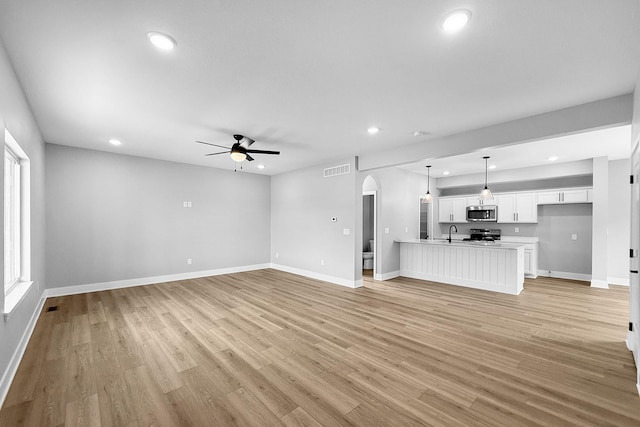 320 Veterans Blvd, Knoxville, IA 50138 - unfurnished living room with ceiling fan, recessed lighting, arched walkways, and light wood-style flooring