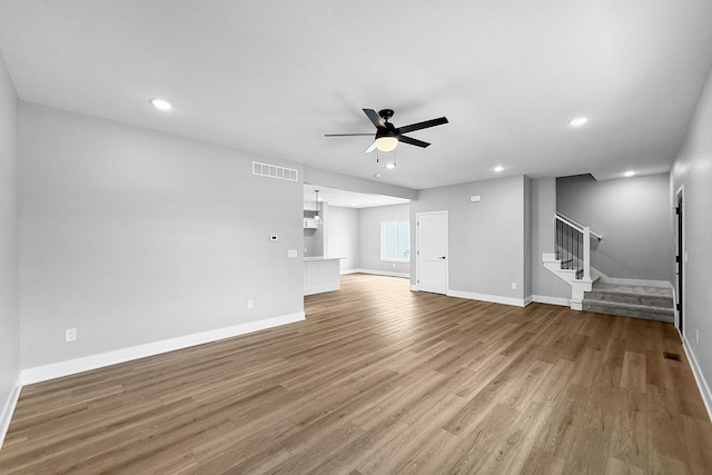 320 Veterans Blvd, Knoxville, IA 50138 - unfurnished living room with a ceiling fan, wood finished floors, stairs, and recessed lighting