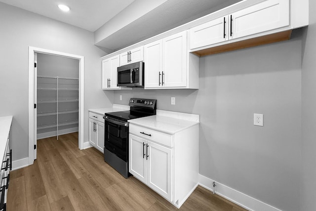 320 Veterans Blvd, Knoxville, IA 50138 - kitchen featuring electric range, stainless steel microwave, light wood-type flooring, white cabinets, and recessed lighting