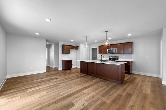 324 Veterans Blvd, Knoxville, IA 50138 - kitchen with appliances with stainless steel finishes, light countertops, recessed lighting, light wood-type flooring, and an island with sink