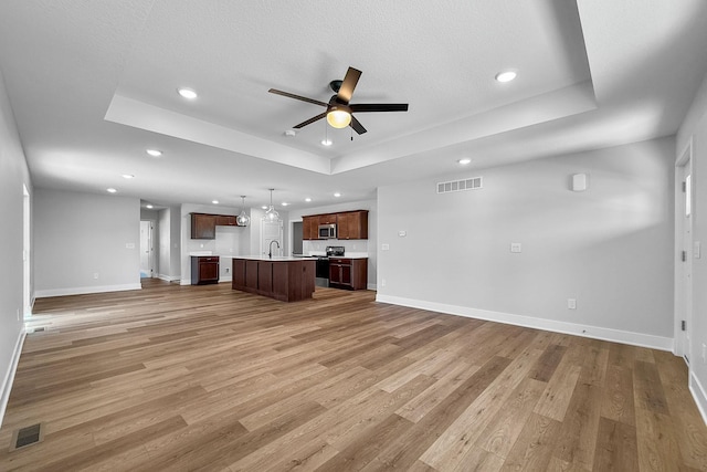 324 Veterans Blvd, Knoxville, IA 50138 - unfurnished living room featuring a raised ceiling, ceiling fan, light wood-type flooring, and recessed lighting