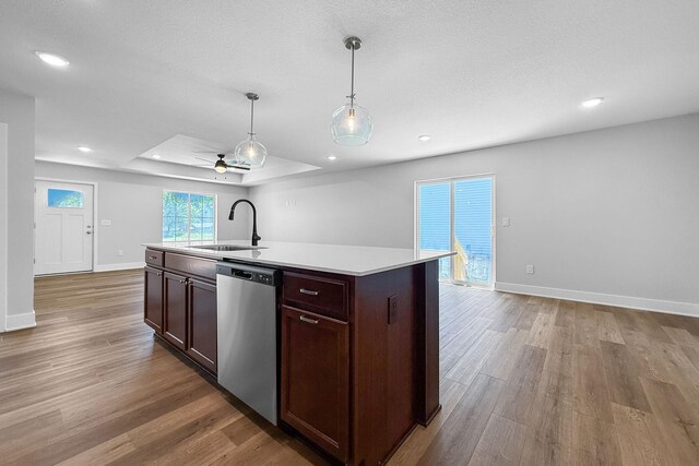 324 Veterans Blvd, Knoxville, IA 50138 - kitchen with stainless steel dishwasher, light wood finished floors, light countertops, a kitchen island with sink, and hanging light fixtures