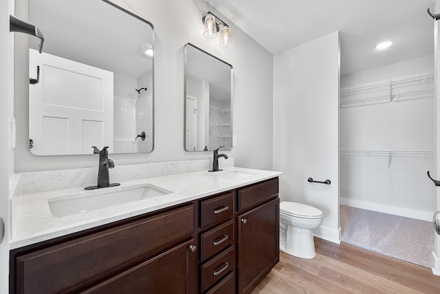 324 Veterans Blvd, Knoxville, IA 50138 - full bathroom featuring double vanity, wood finished floors, a walk in closet, and a shower