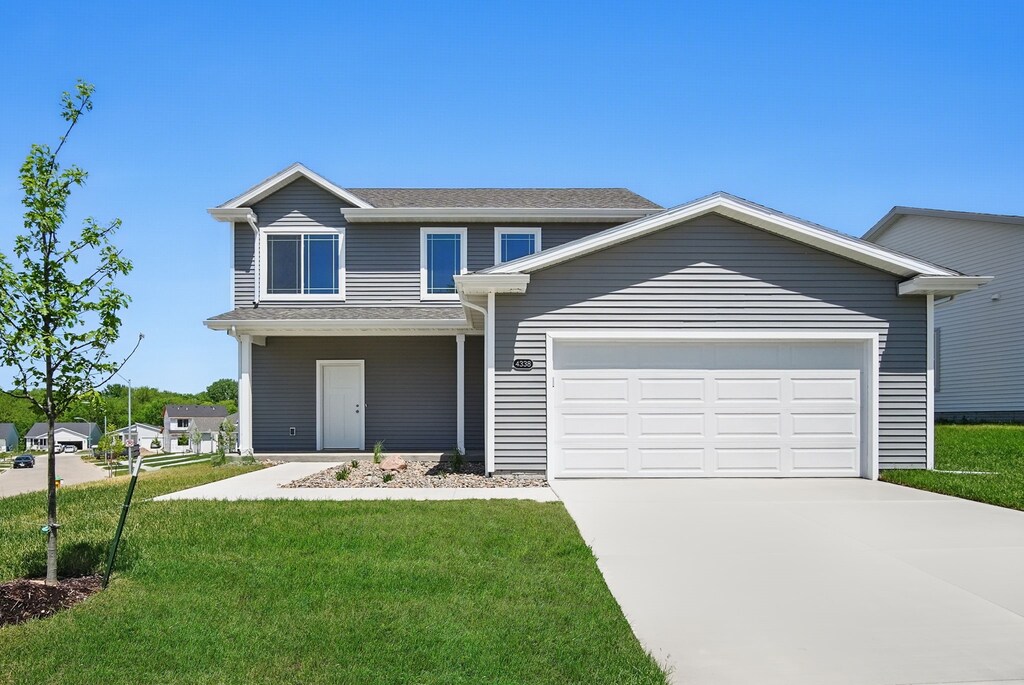 4338 Grover Woods Ln, Des Moines, IA 50317 - view of front of home with concrete driveway, a front lawn, and a garage