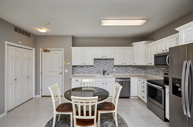 1325 SE Florence Dr Unit 211, Waukee, IA 50263 - kitchen with appliances with stainless steel finishes, light tile patterned floors, visible vents, decorative backsplash, and a sink