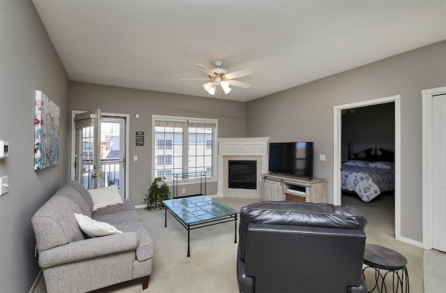 1325 SE Florence Dr Unit 211, Waukee, IA 50263 - living area with baseboards, a ceiling fan, a glass covered fireplace, and light carpet