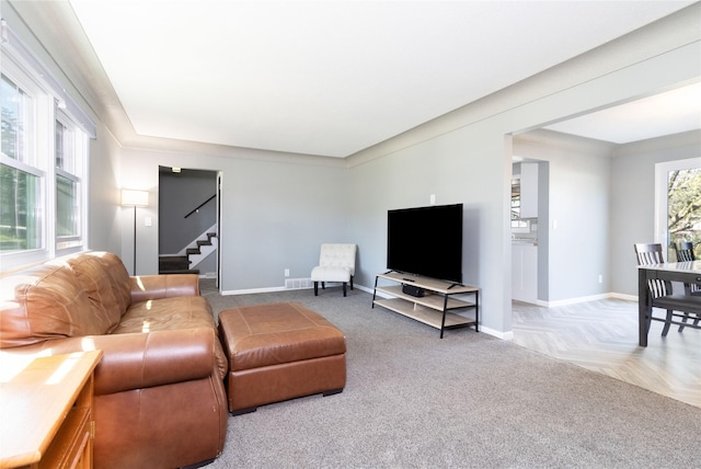 living area with visible vents, baseboards, carpet, and stairway