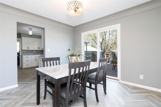 dining room featuring a notable chandelier and baseboards