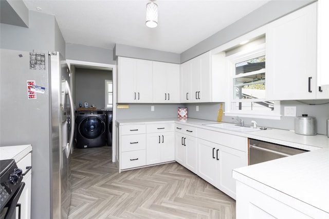 kitchen featuring a sink, light countertops, appliances with stainless steel finishes, a wealth of natural light, and washing machine and clothes dryer