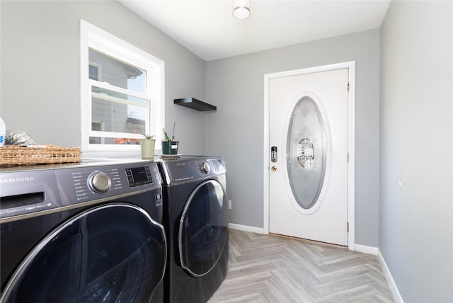 clothes washing area with baseboards, washer and clothes dryer, and laundry area