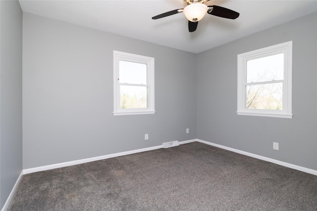unfurnished room featuring baseboards, dark colored carpet, and visible vents